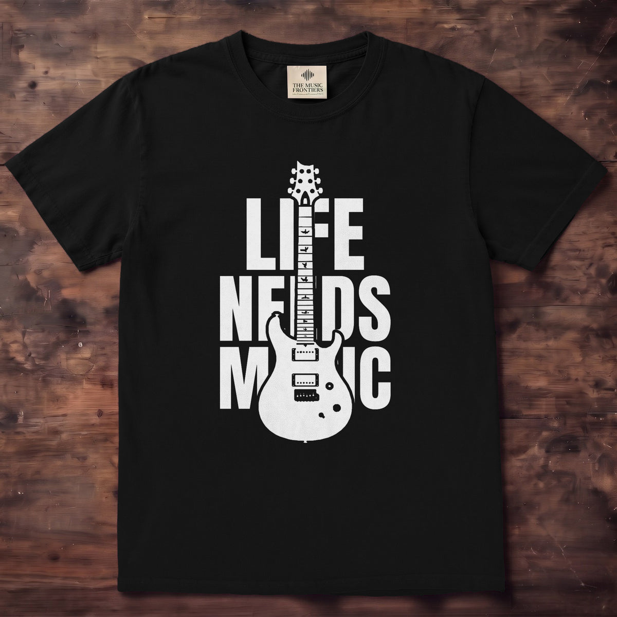 Ivory tee with LIFE NEEDS MUSIC in bold black letters and a guitar cutting through the middle