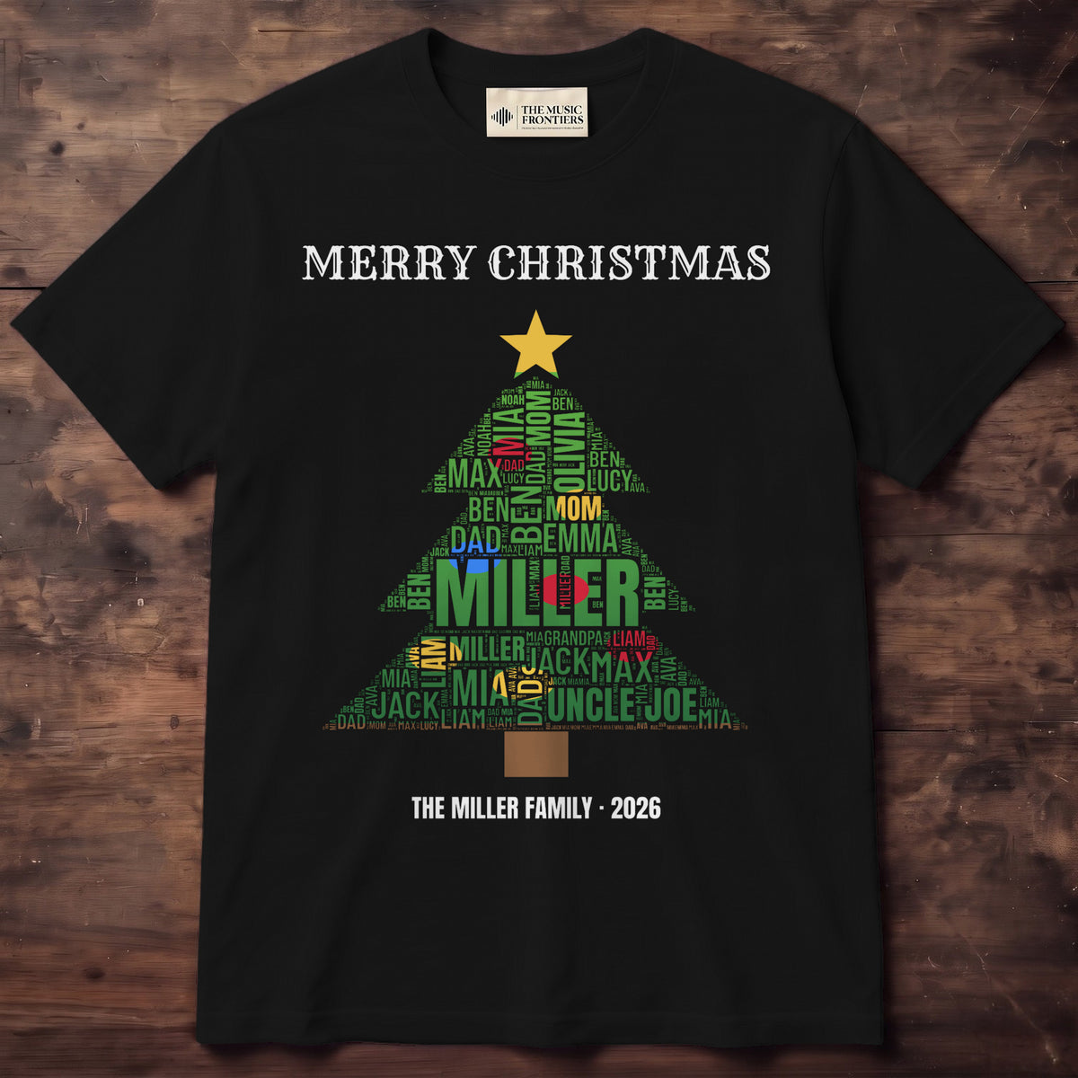 Black tee with family names forming a green Christmas tree with red and gold ornaments, a gold star and The Miller Family 2026