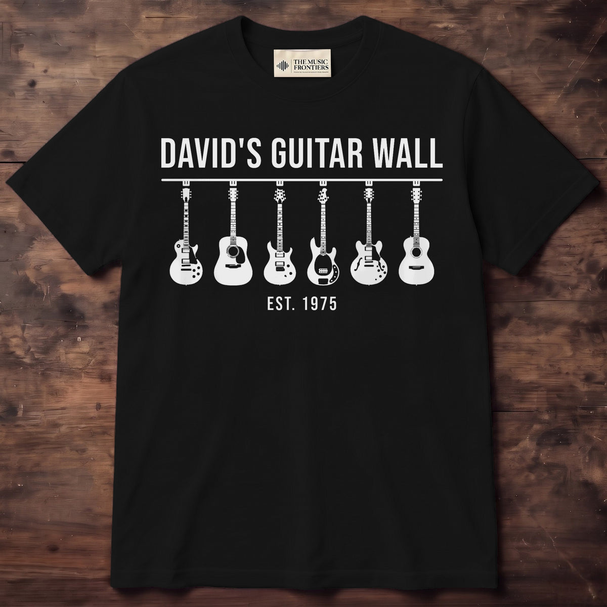 Black shirt printed with a wall of guitars hanging in a row, a name and an EST year